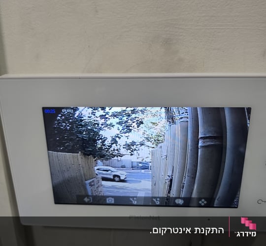 מסך אינטרקום פנימי מותקן על קיר ומציג תמונה ממצלמת כניסה